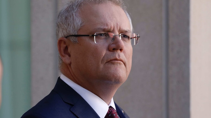 Scott Morrison in a dark blue suit and maroon tie, looks off into the distance.