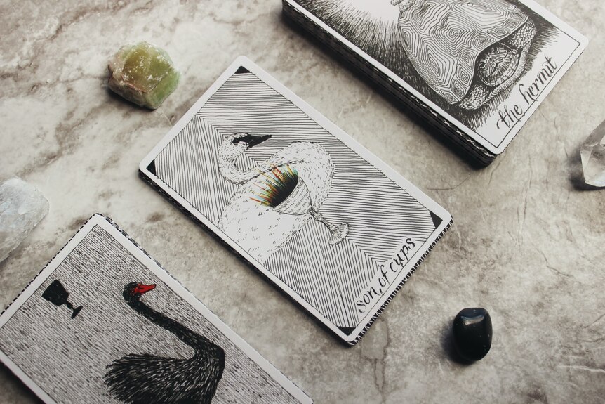 Tarot cards on a marble surface with a green and clear crystal.