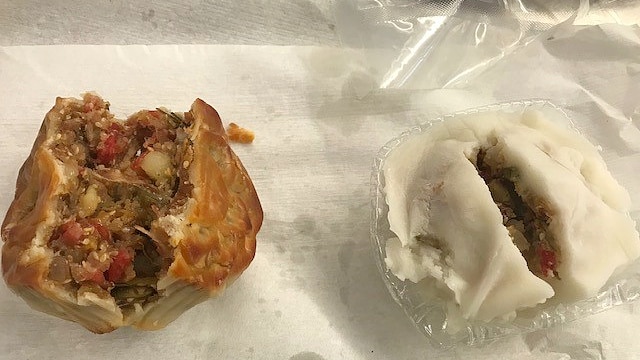 Close up photo of two mooncakes which have pastry on the outside and meat and vegetables inside