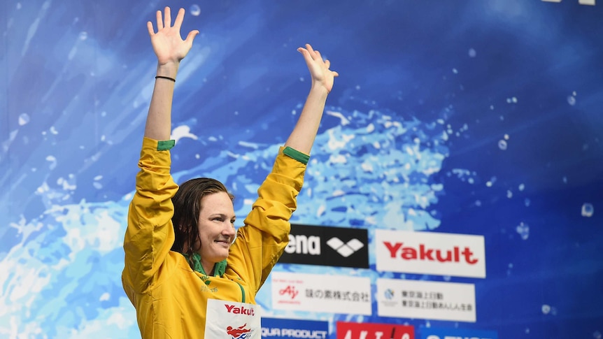 Cate Campbell raises her arms on the podium.