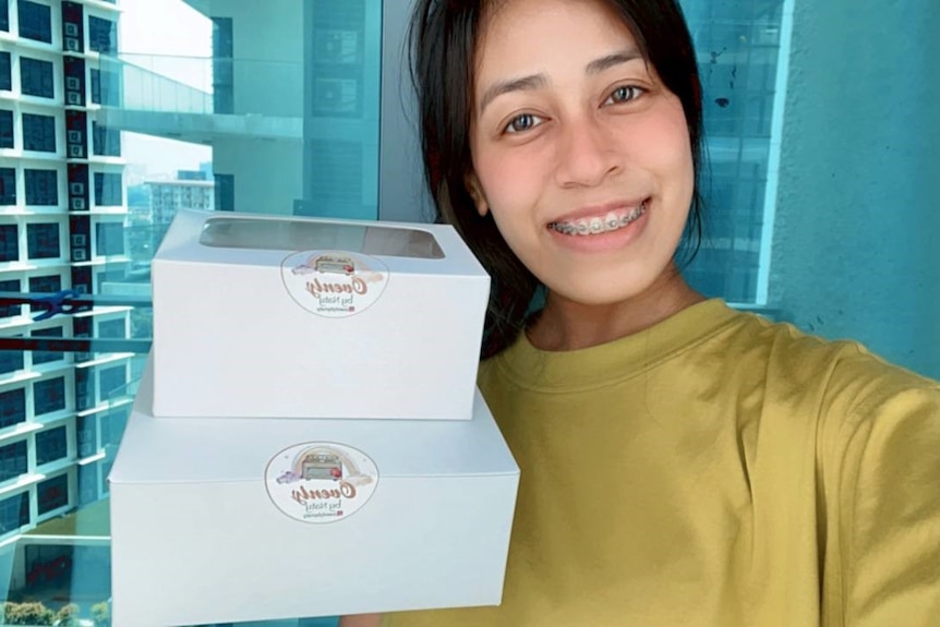 A girl with braces holding up two boxes of cookies.