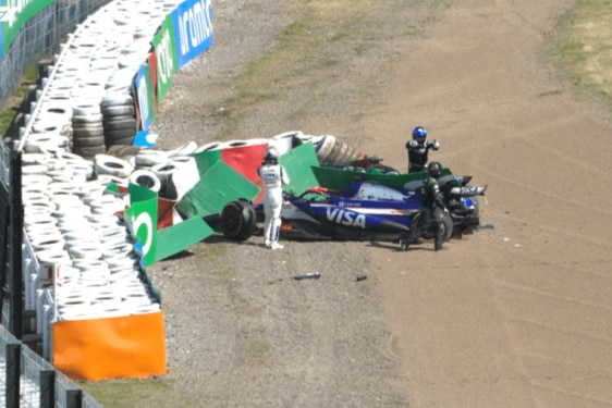 An F1 car in a gravel trap, after hitting barriers, with the driver out of the car