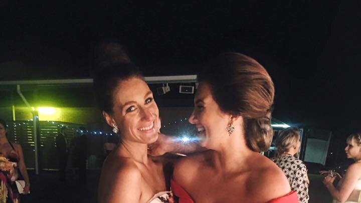 Two young women in glamorous ball gowns at a charity ball