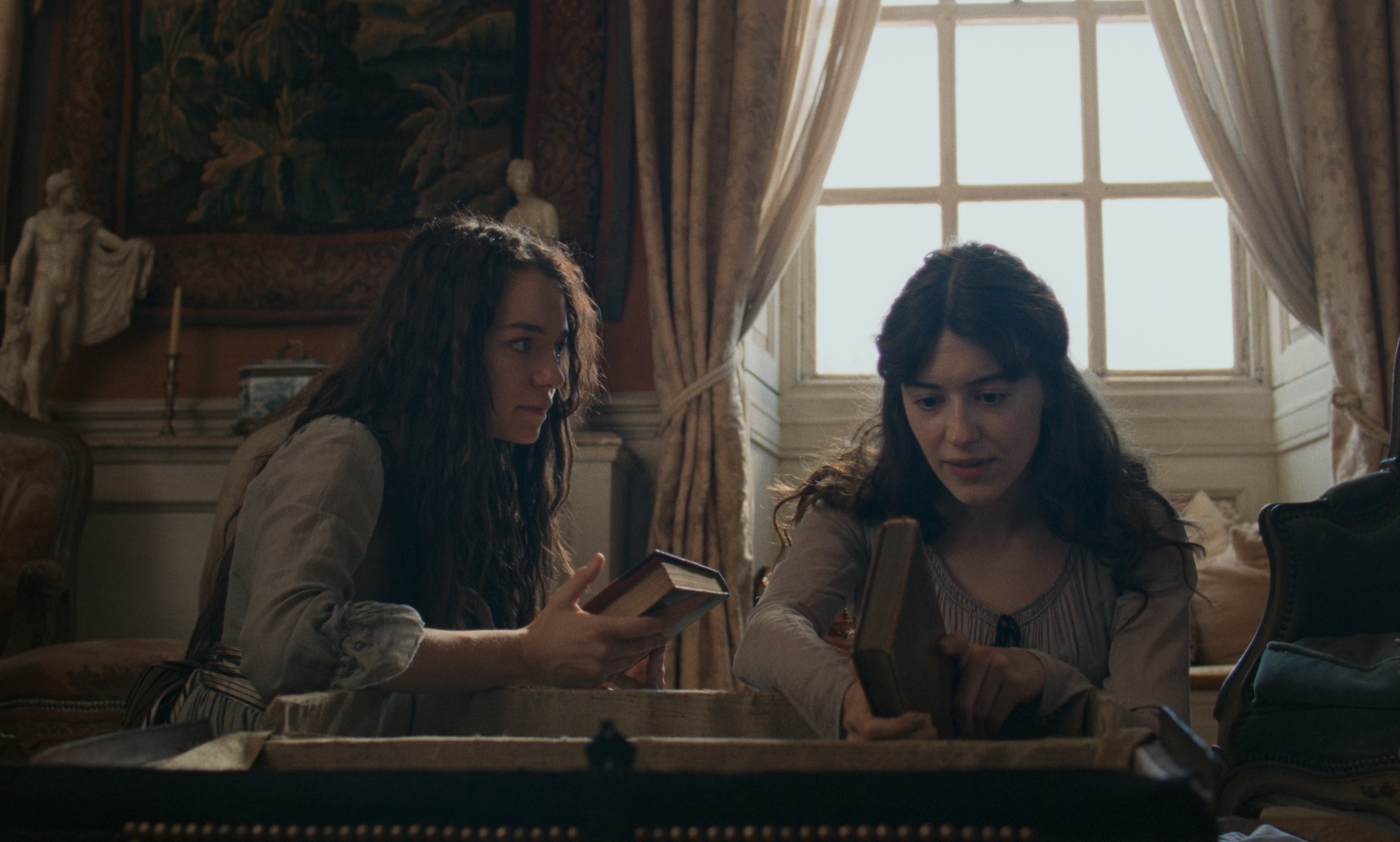 Two young women look over some books in a trunk