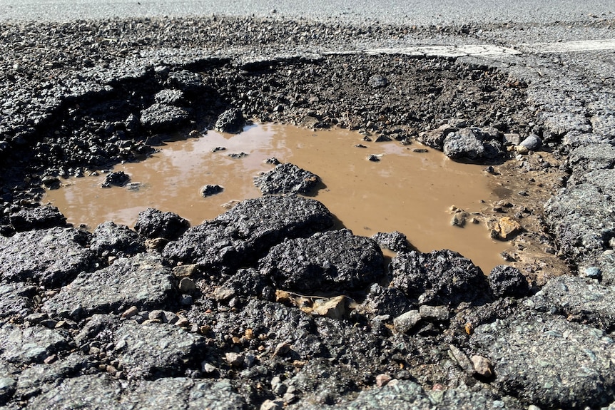 Large road pothole that's filled with water.