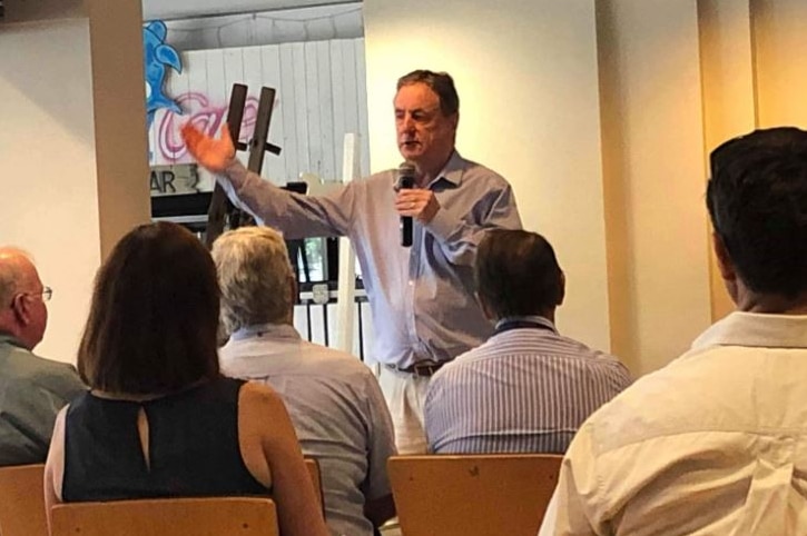 Mick Keelty raises a hand as he talks to people during a town hall meeting in Renmark.