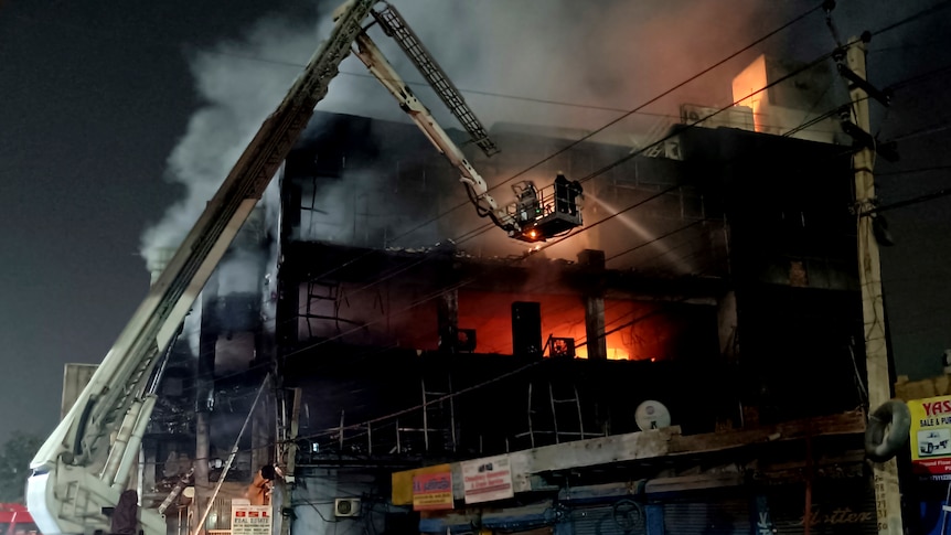 Fire fighters attempt to douse fire from crane at night.
