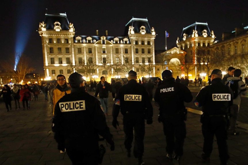 Four police officers stand outside the Notre Dame cathedral as worshippers gather.