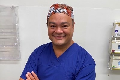 An Aboriginal doctor in blue scrubs.
