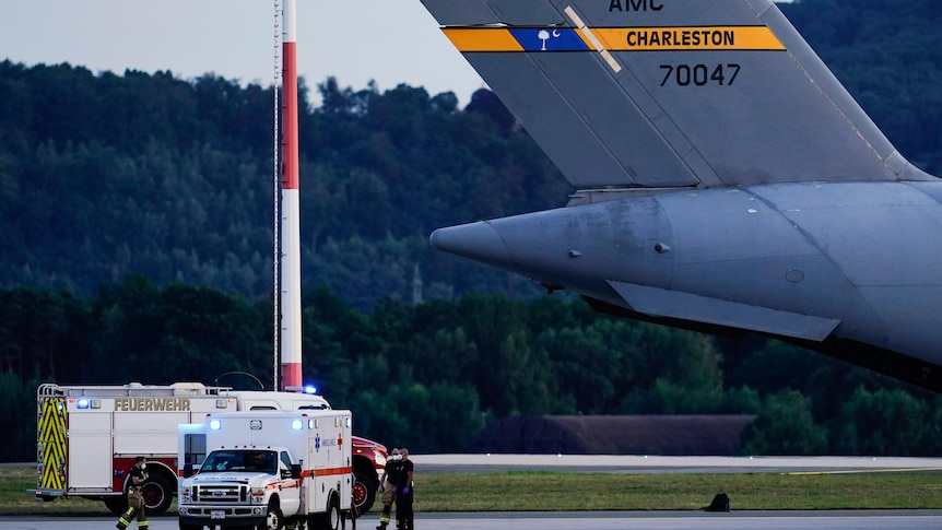 An ambulance stands next to a transport plane carrying people flown out of Afghanistan