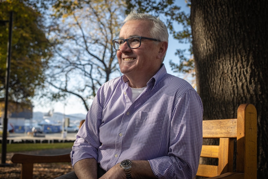 Andrew Wilkie sits on a chair in a park.