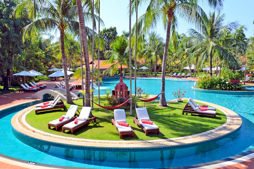 deck chairs and palm trees surround a pool at the Sofitel Angkor Pokheethra Golf and Spa Resort.
