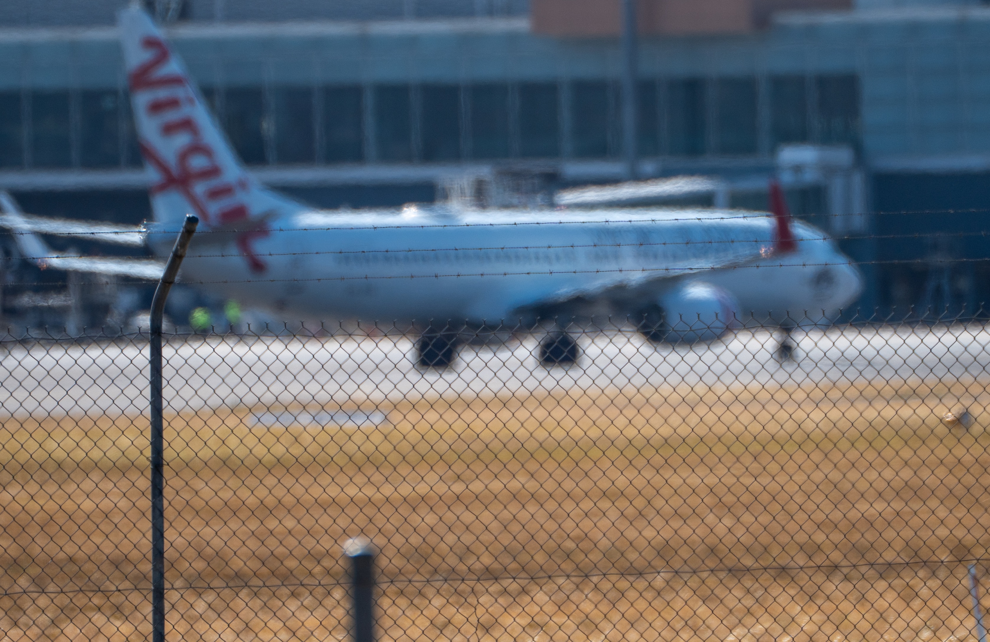 Un avión de Virgin desde la distancia con un edificio del aeropuerto detrás