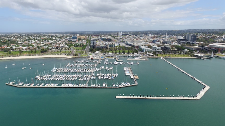 Geelong's waterfront, harbour and city shown from the ocean on a blue sky day.