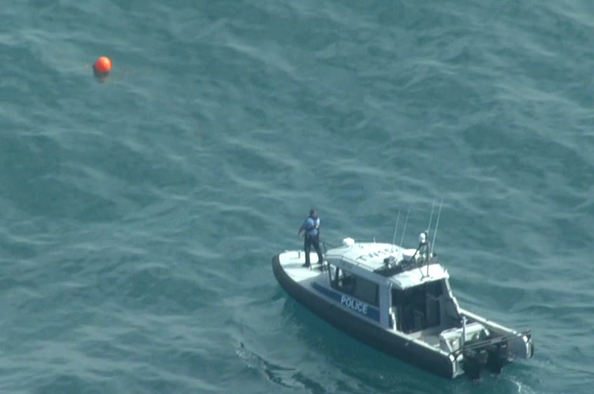 An aerial shot of a water police boat next to a floating red buoy.