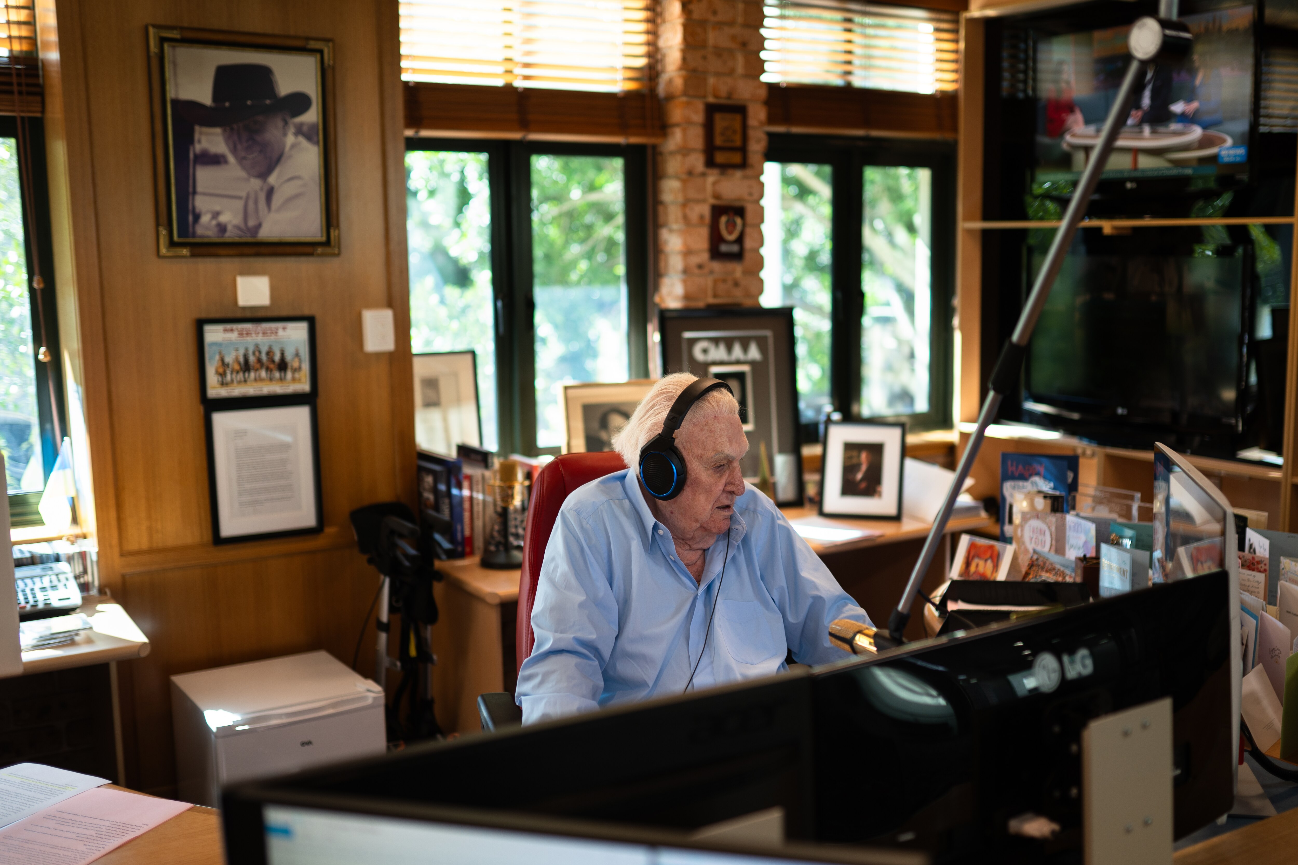 An older man with grey hair speaks into a mic in a radio studio.