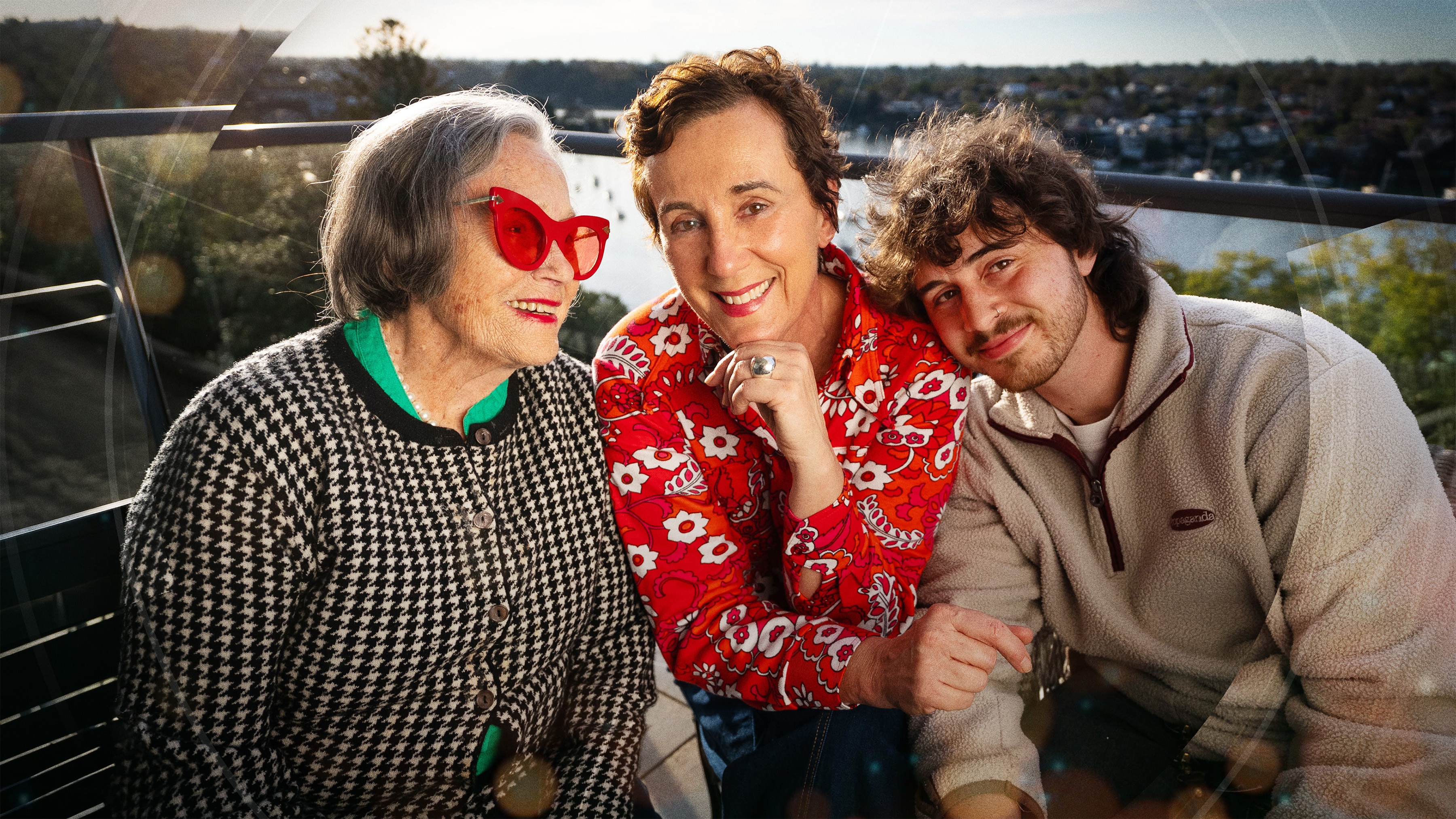 Elderly woman, middle aged woman and man in his 20's on a balcony with water behind them