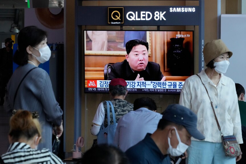 People watch a TV that has Kim Jong Un on it