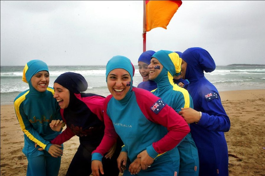 Women wear colourful burkinis on a beach