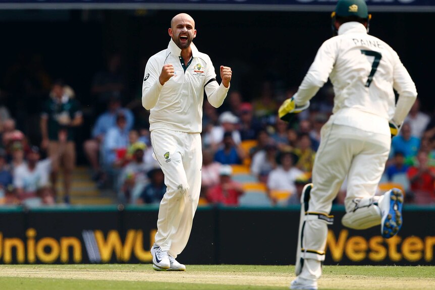 Nathan Lyon clenches his fists and roars in delight as Tim Paine runs to celebrate with him.