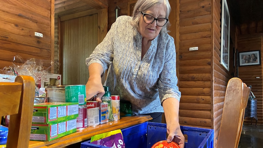 Middl-aged woman places food items in box for charity
