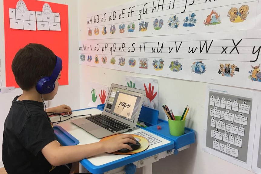 Queensland distance education student Bryce Magerl, 7, sits at a desk on a computer.