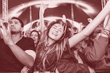 A woman with her eyes closed dances in the front row of a music festival