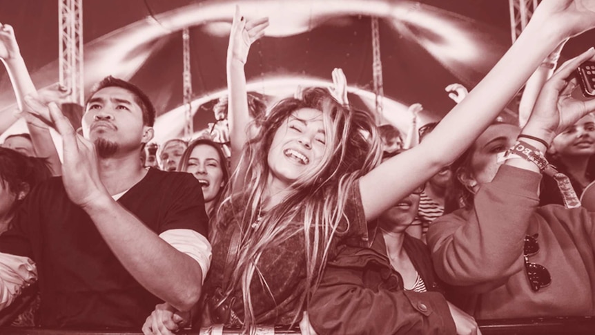 A woman with her eyes closed dances in the front row of a music festival
