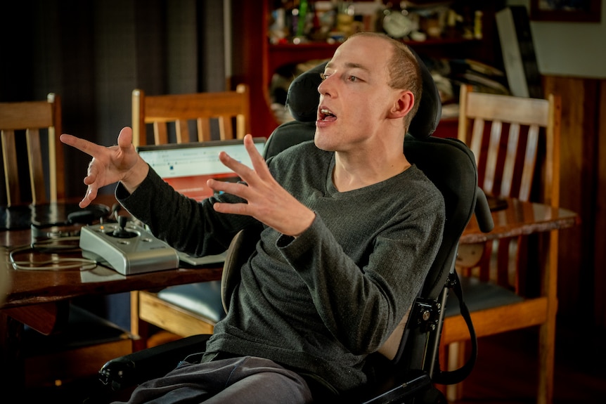 Nathan Johnston gesturing with his hands as he speaks, he's near a dining room table.