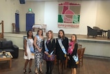 The entrants of the 2017 Gulargambone Showgirl competition stand in a community hall with sashes.