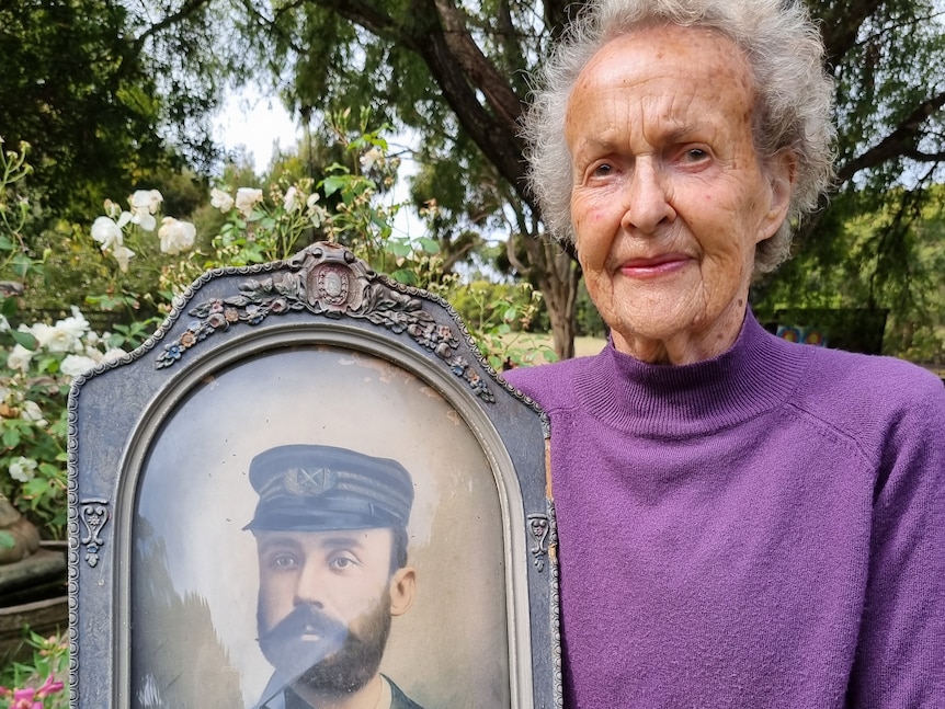older woman holding old photograph of captain
