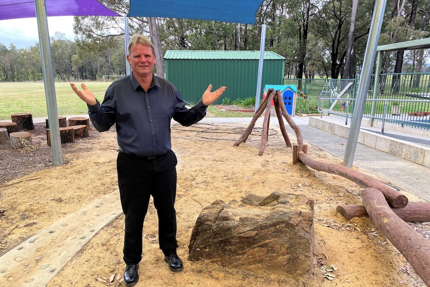 An older man stands in a primary school playground.