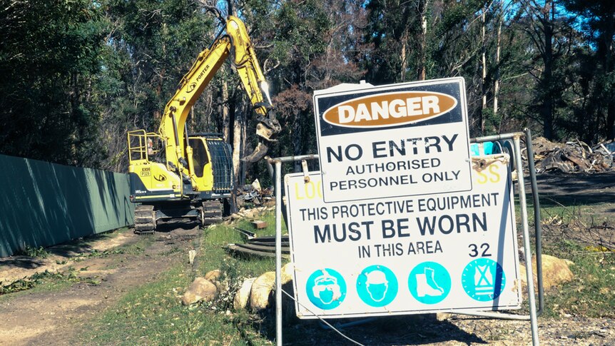 Danger No Entry sign with excavator in the background clearing a property