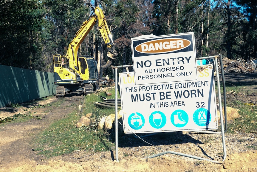 Danger No Entry sign with excavator in the background clearing a property