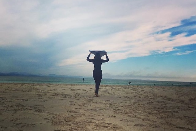 Female surfer Thais Pupio with her longboard at The Pass in Byron Bay.