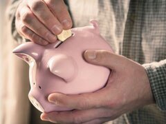 Man holding piggy bank and putting in money