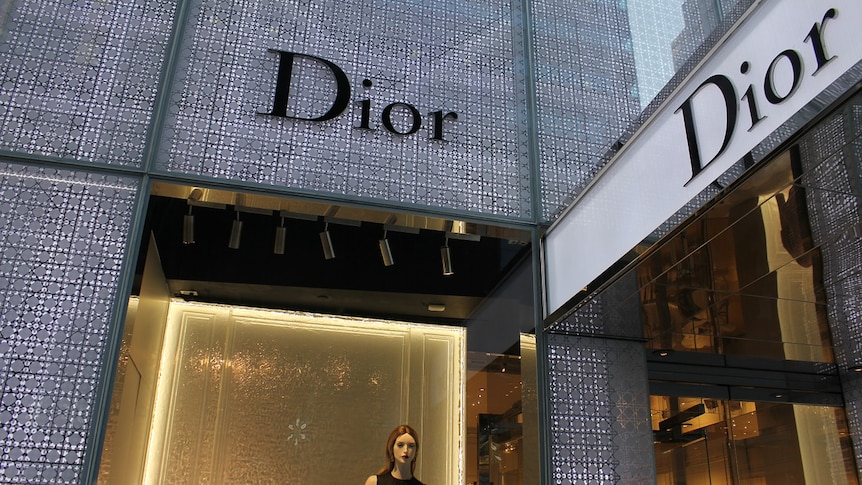 The torso and head of a mannequin can be seen in a window at a Dior shopfront in New York City.