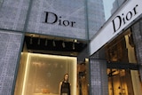 The torso and head of a mannequin can be seen in a window at a Dior shopfront in New York City.