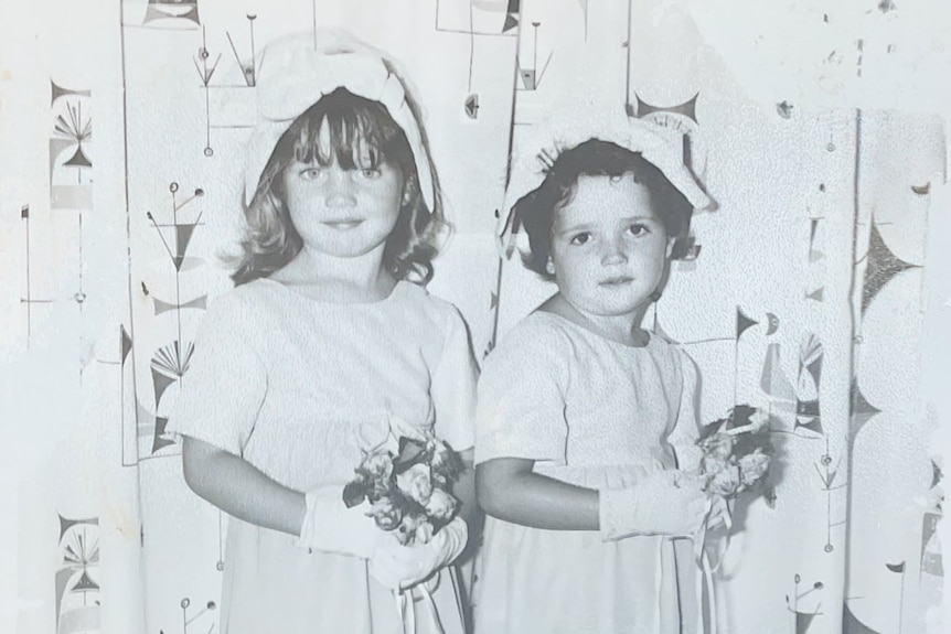 Black and white image of Megan (left) and sister dressed up for church as young girls