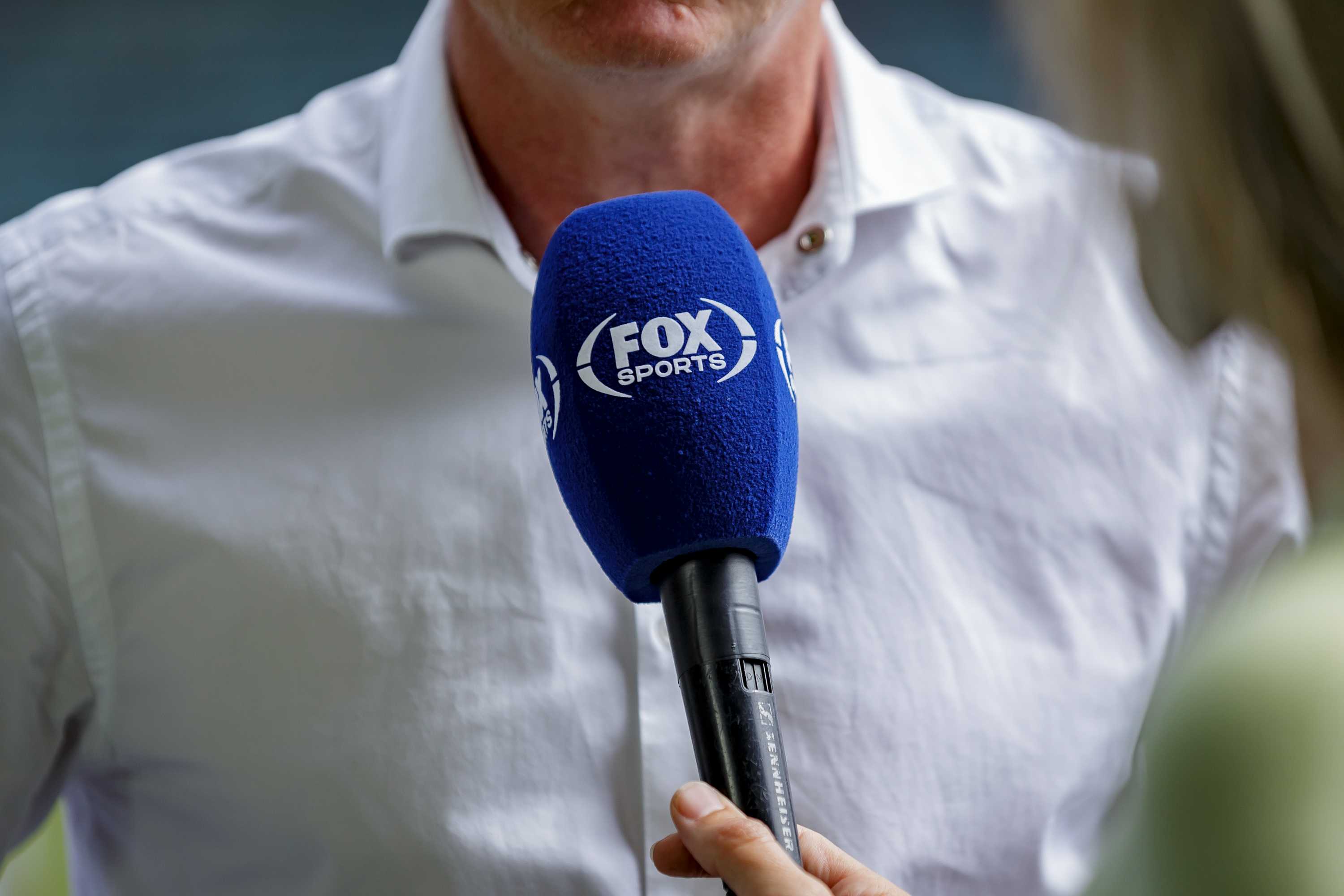 Microphone saying Fox Sports in front of man in business shirt on sports field