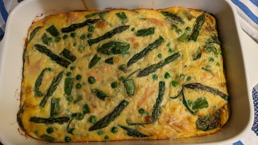 A ceramic, rectangular baking dish with an egg and asparagus frittata in it.