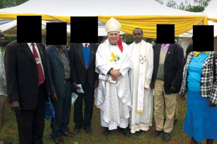 Two men in religious regalia stand alongside other people at a public event.