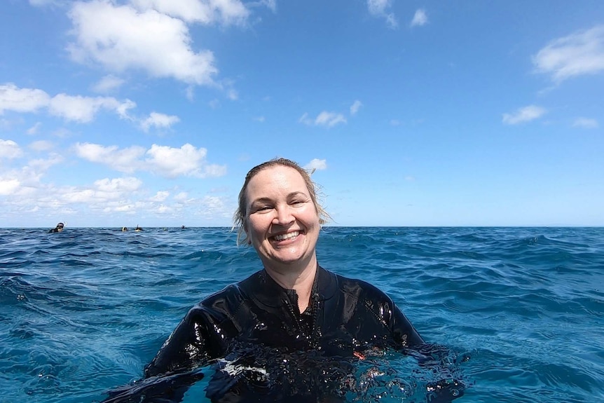 a woman is swimming in the ocean smiling at the camera