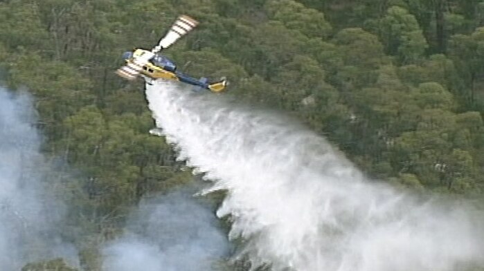 A helicopter drops water on the fire burning in bushland at Benloch in central Victoria.