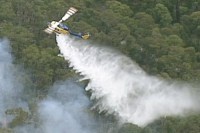 A helicopter drops water on the fire burning in bushland at Benloch in central Victoria.