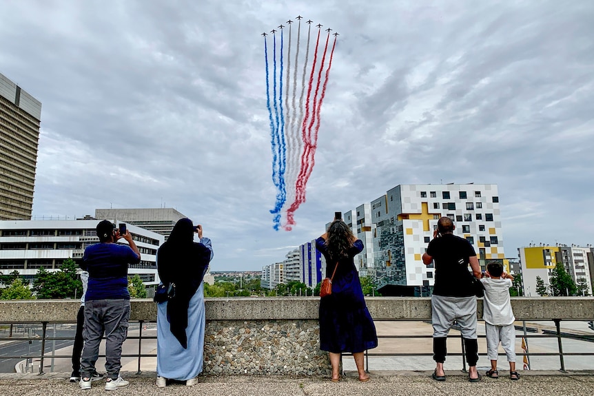 Residents watch jets from Patrouille de France flying over Paris