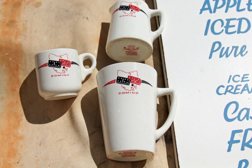 Three white cups with red writing saying Domino on them