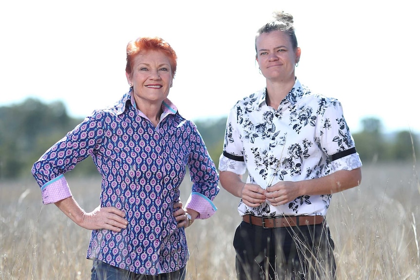 Two women stand together in a field.