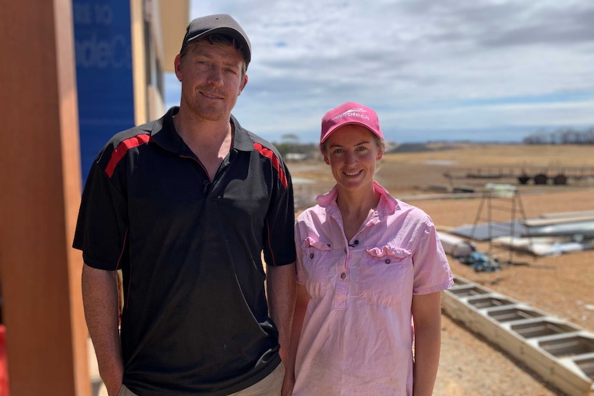 A man and woman stand next to each other on a building site.