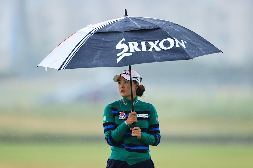 Minjee Lee holds an umbrella